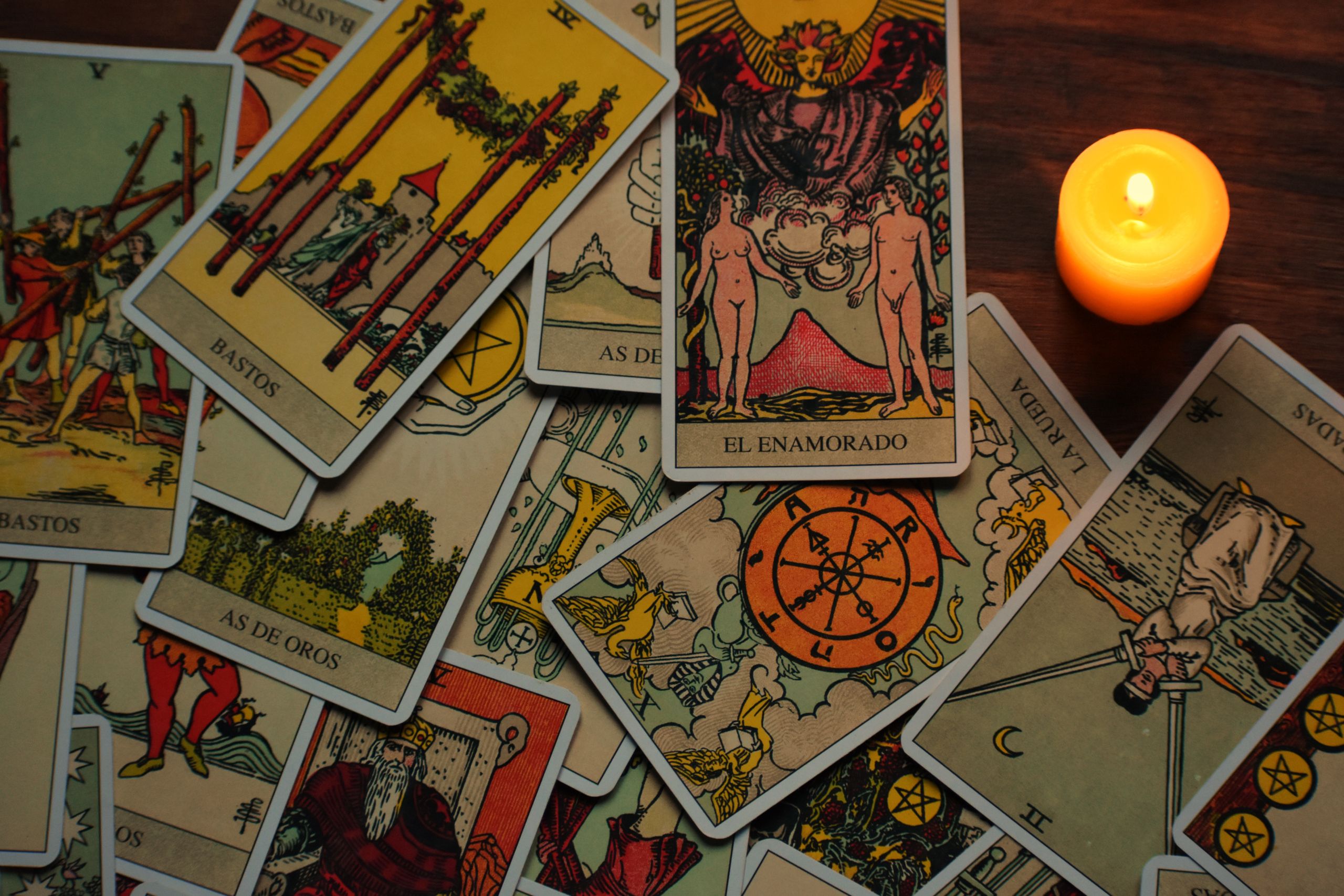 A collection of tarot cards arranged under the light of a burning candle.