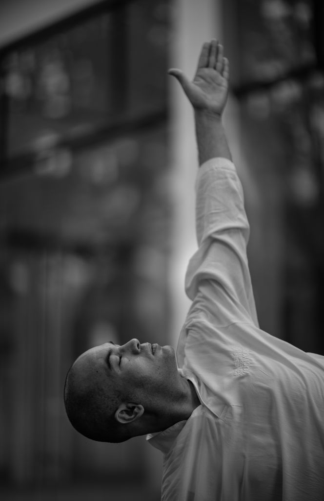 Monochrome image of a man with eyes closed, arm raised, lost in thought.