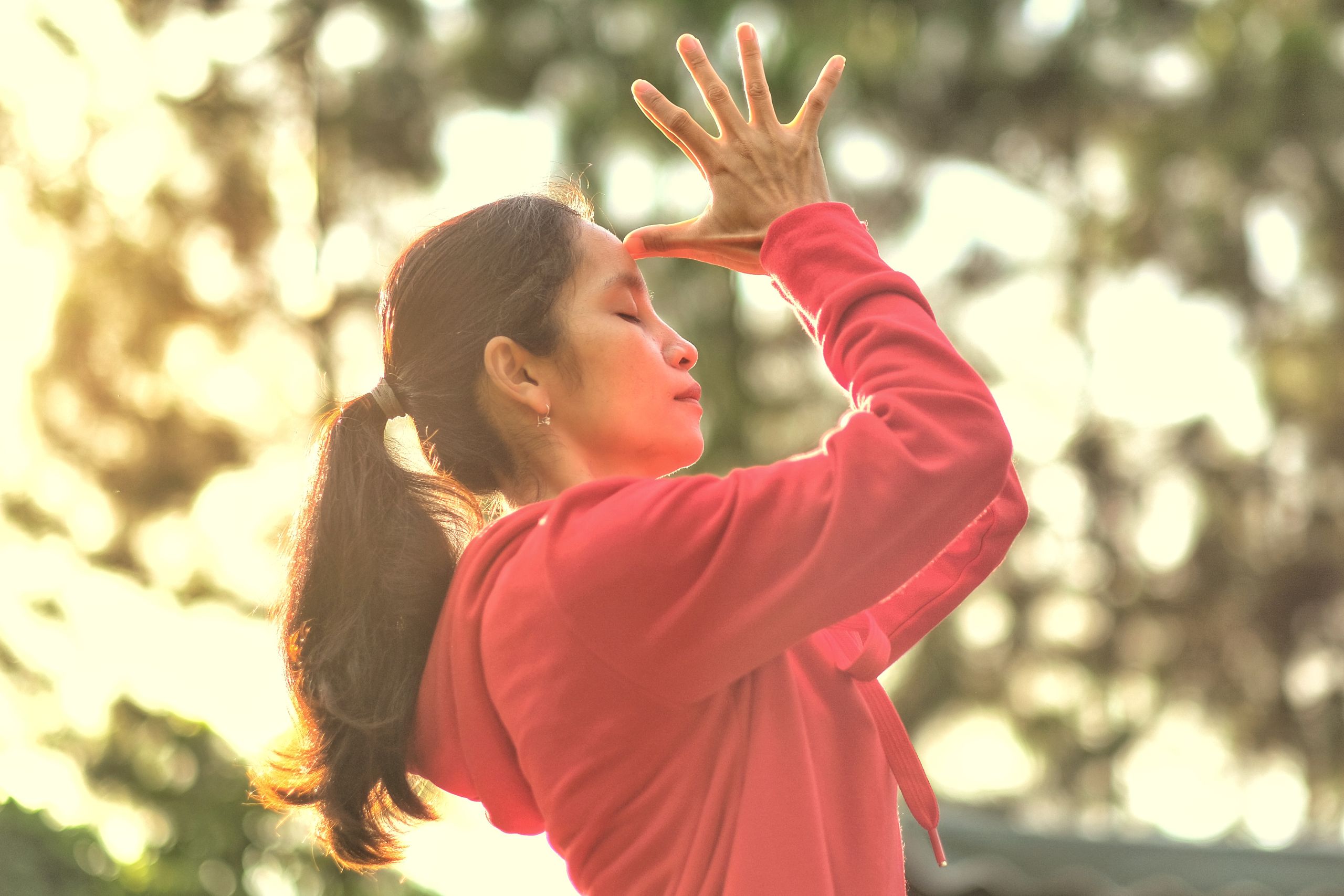 Woman practicing mindful meditation outdoors with sunlight and nature in the background.